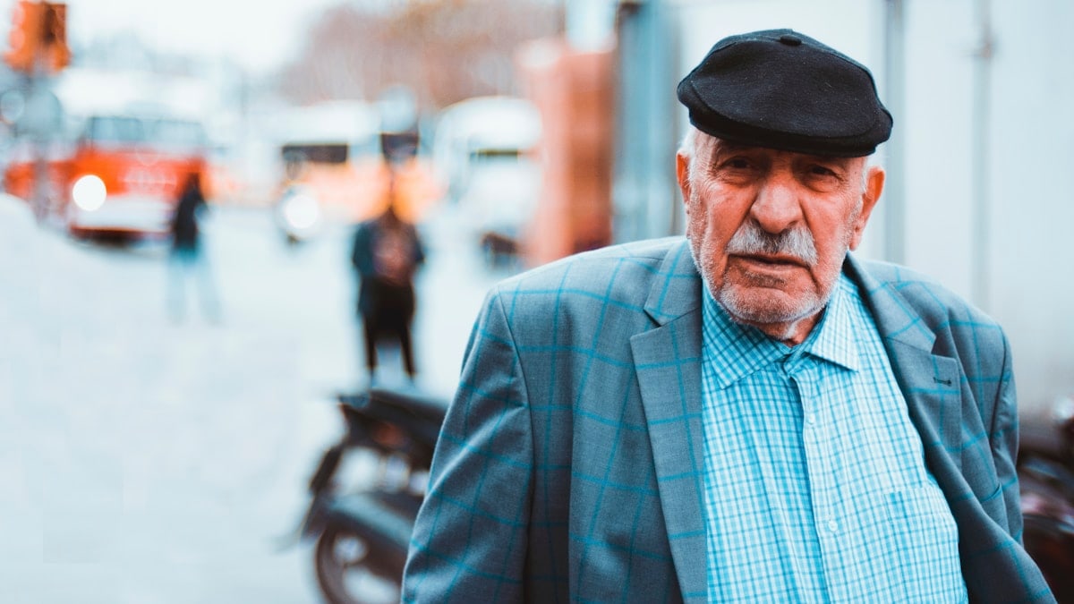 man in blue and white plaid dress shirt wearing black fedora hat